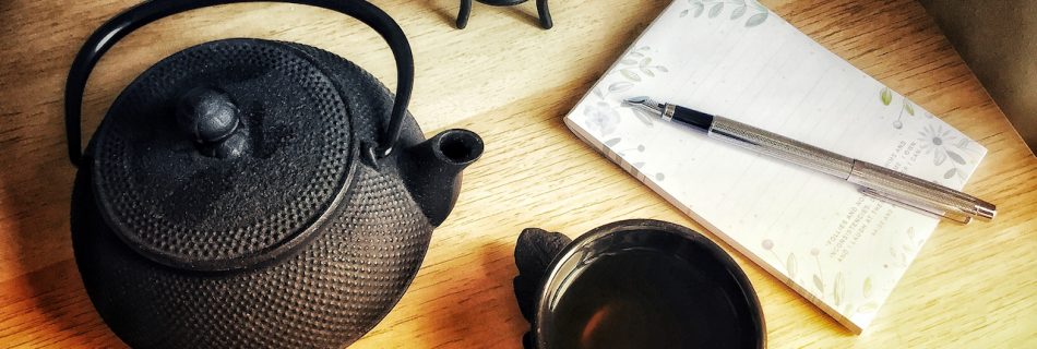 Photograph of an iron teapot and notebook