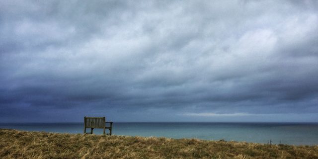 Seascape Moody Sky Upton Bude Cornwall A empty bench is on the cliff looking out on a stormy sky.