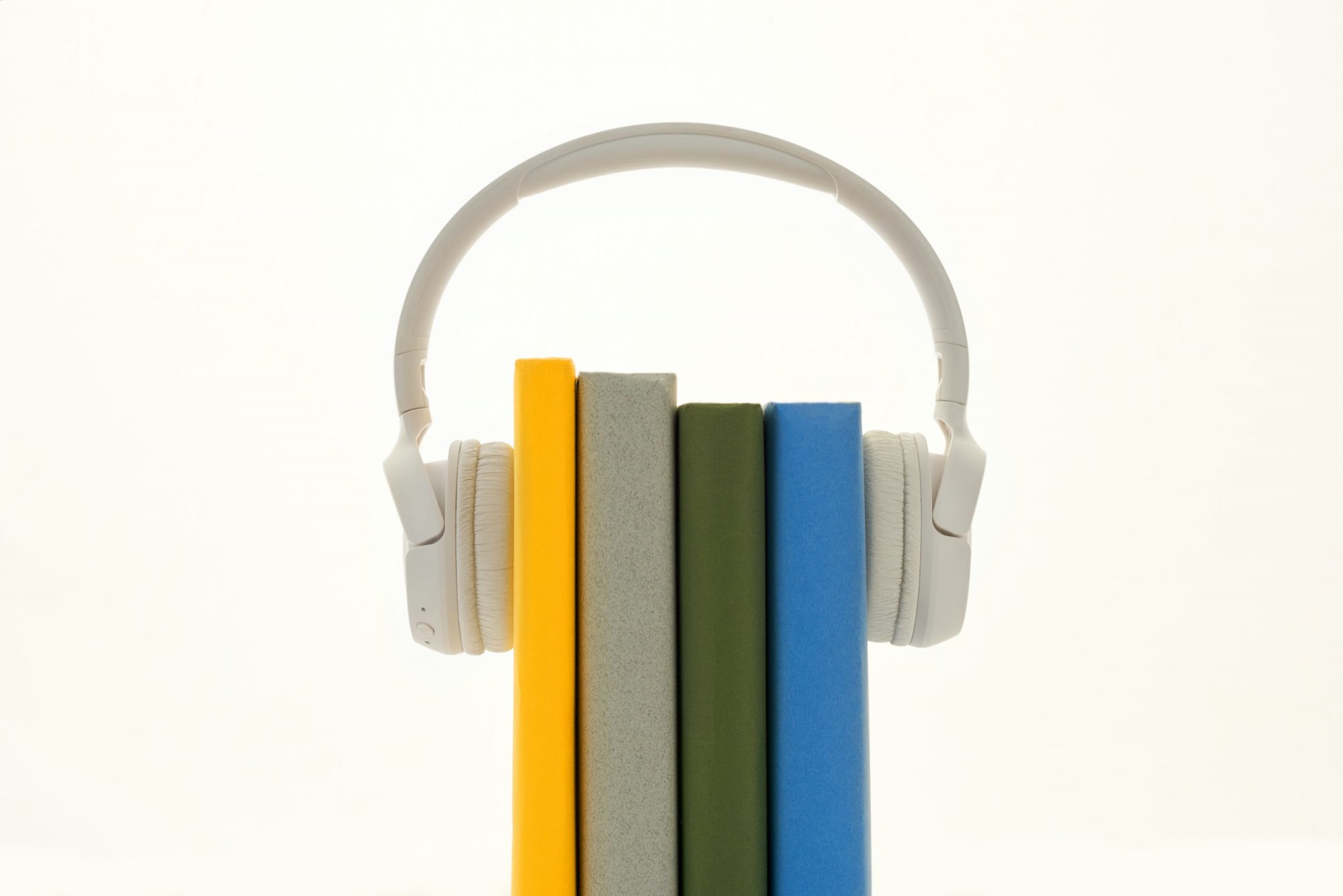 Four colourful books between a pair of white headphones