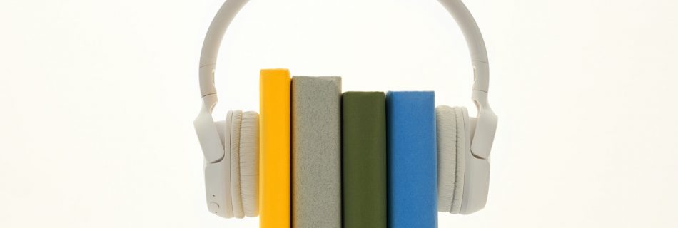 Four colourful books between a pair of white headphones