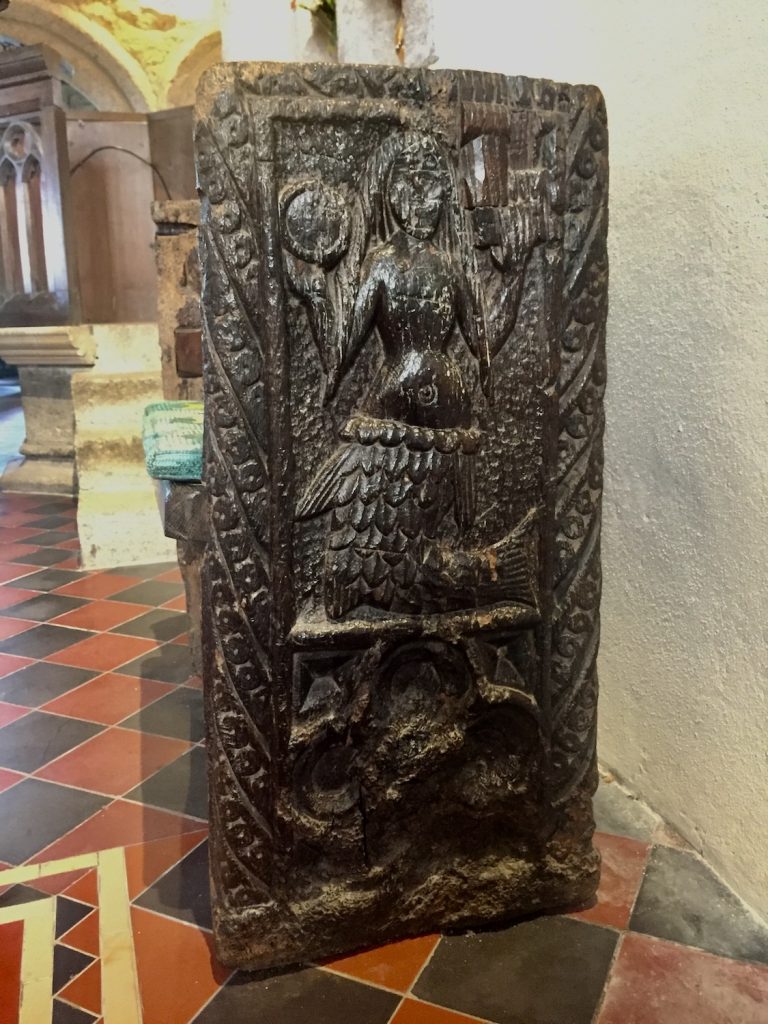 A photograph of a 15th century carving of a mermaid holding a mirror and a comb