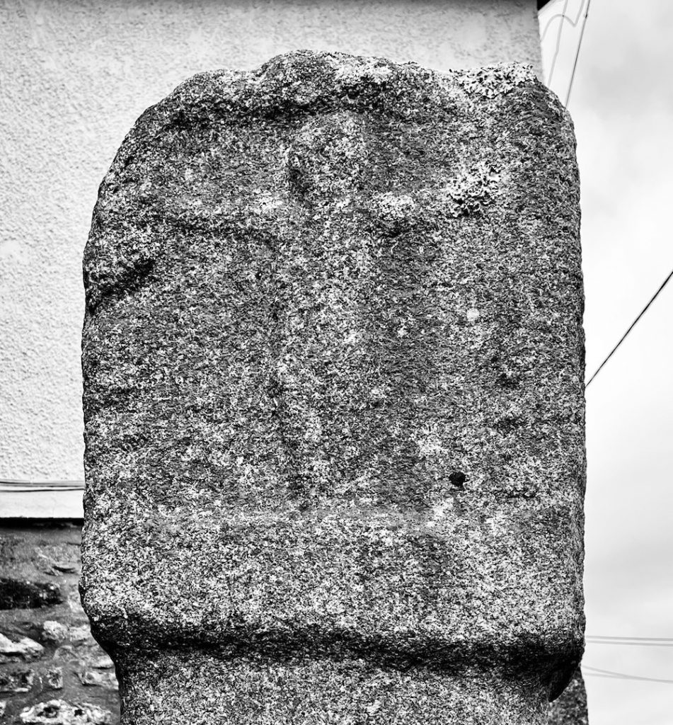 granite cross in black and white showing a worn relief of Jesus on the cross