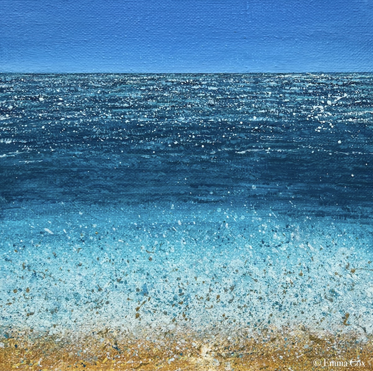 A seascape with a wave crashing on a sandy shore. The horizon is clear blue sky and the sun glitters on the water.