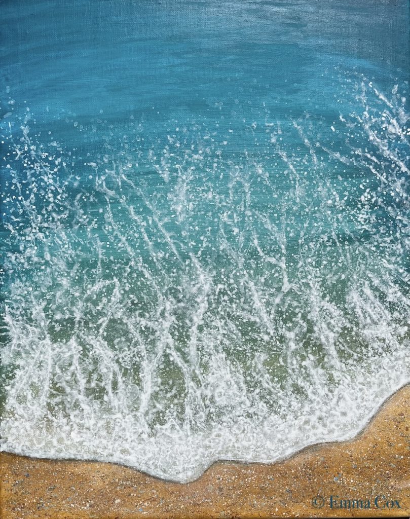 A foamy waves breaks on a sandy shoreline