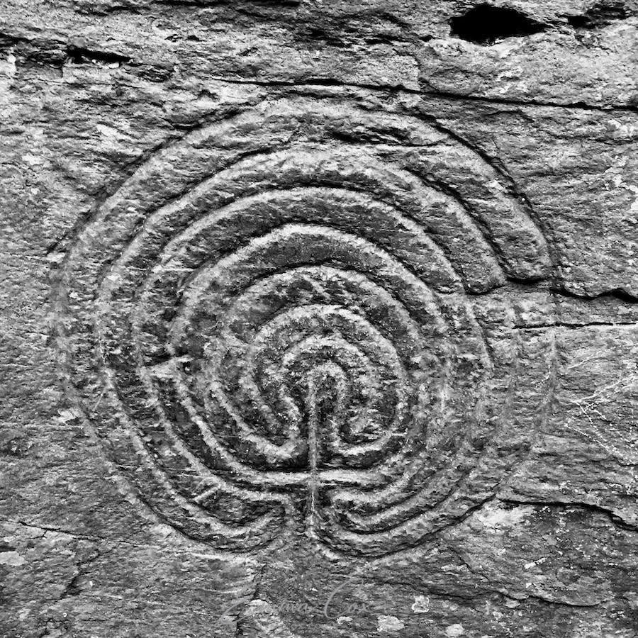 A black and white photograph of a maze/labyrinth symbol carved into the rock at rocky valley, Cornwall.