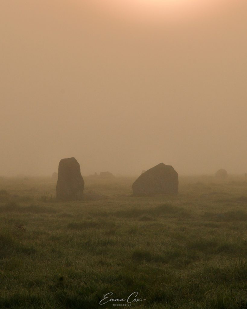 A photograph of the Cornish misty moor at dawn. Two standing stones from a stone circle are visible.