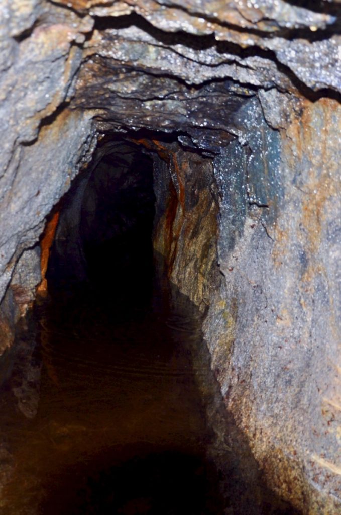 Photograph inside a Cornish mine tunnel which is partly flooded.