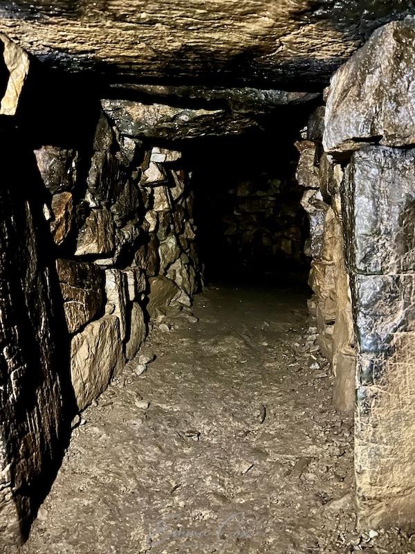 photograph of an underground passageway with drystone walls and a stone lintel ceiling