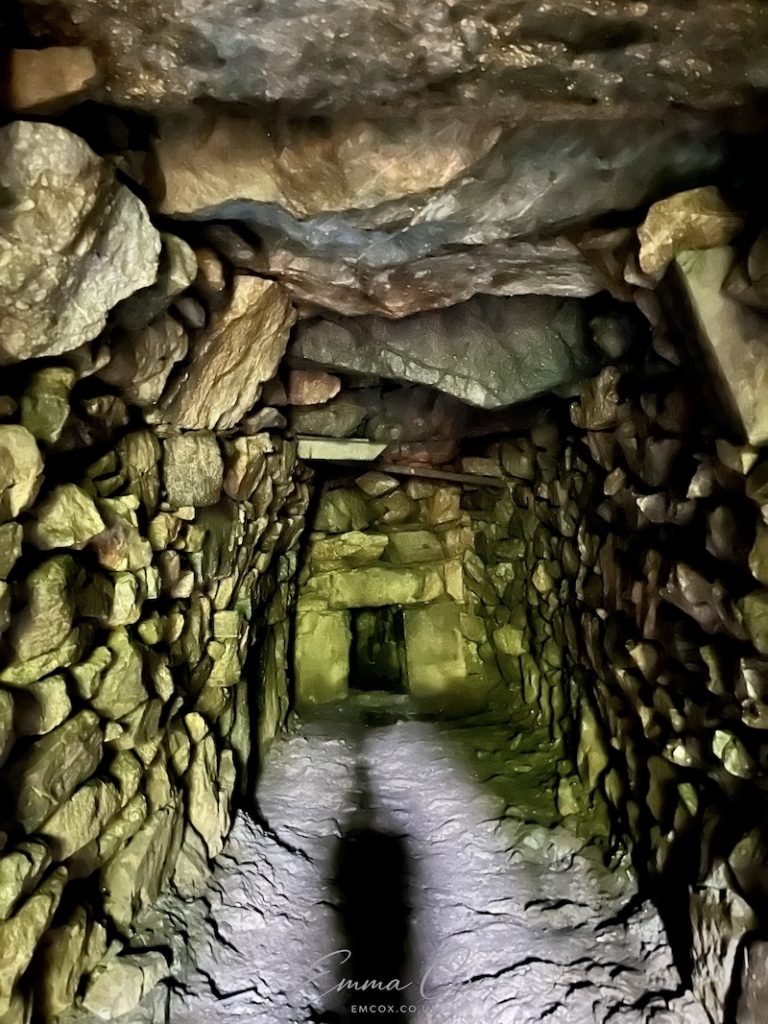 photograph of an underground passageway with drystone walls and a stone lintel ceiling