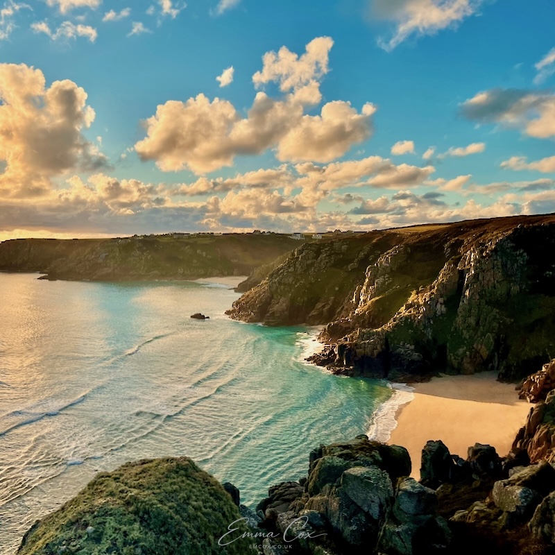 View on cliffs looking towards Porthcurno and Minack Theatre at sunset.