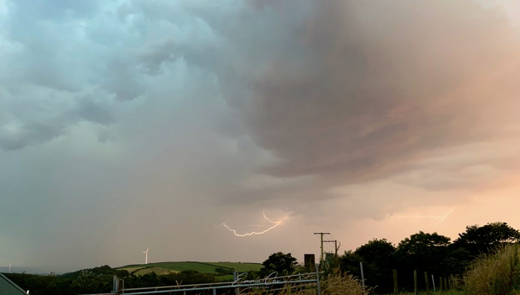 A dusky sky of blue/pink clouds with fork lightning.