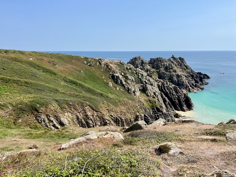 Granite headland showing ditches and ramparts in the grassy foreground.