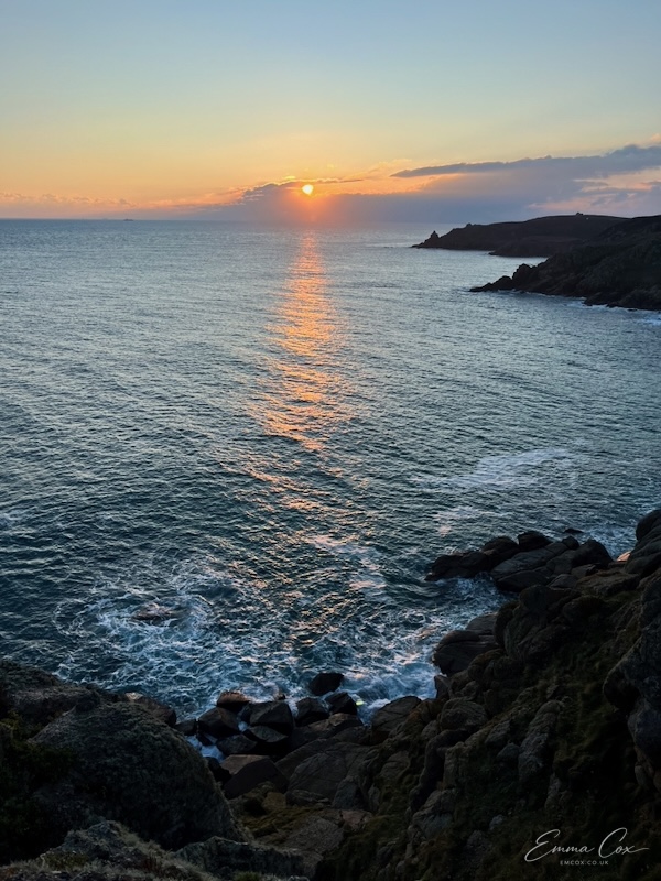 sun setting over the sea with a distant headland