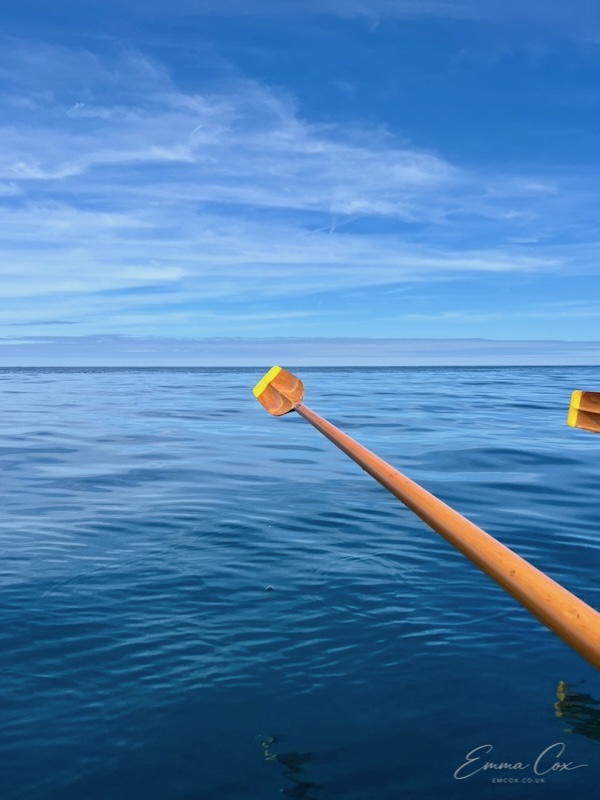 Glassy water in the bay with an oar in the foreground
